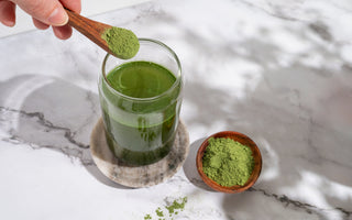 Hand pouring green algae powder into a glass filled with water. 